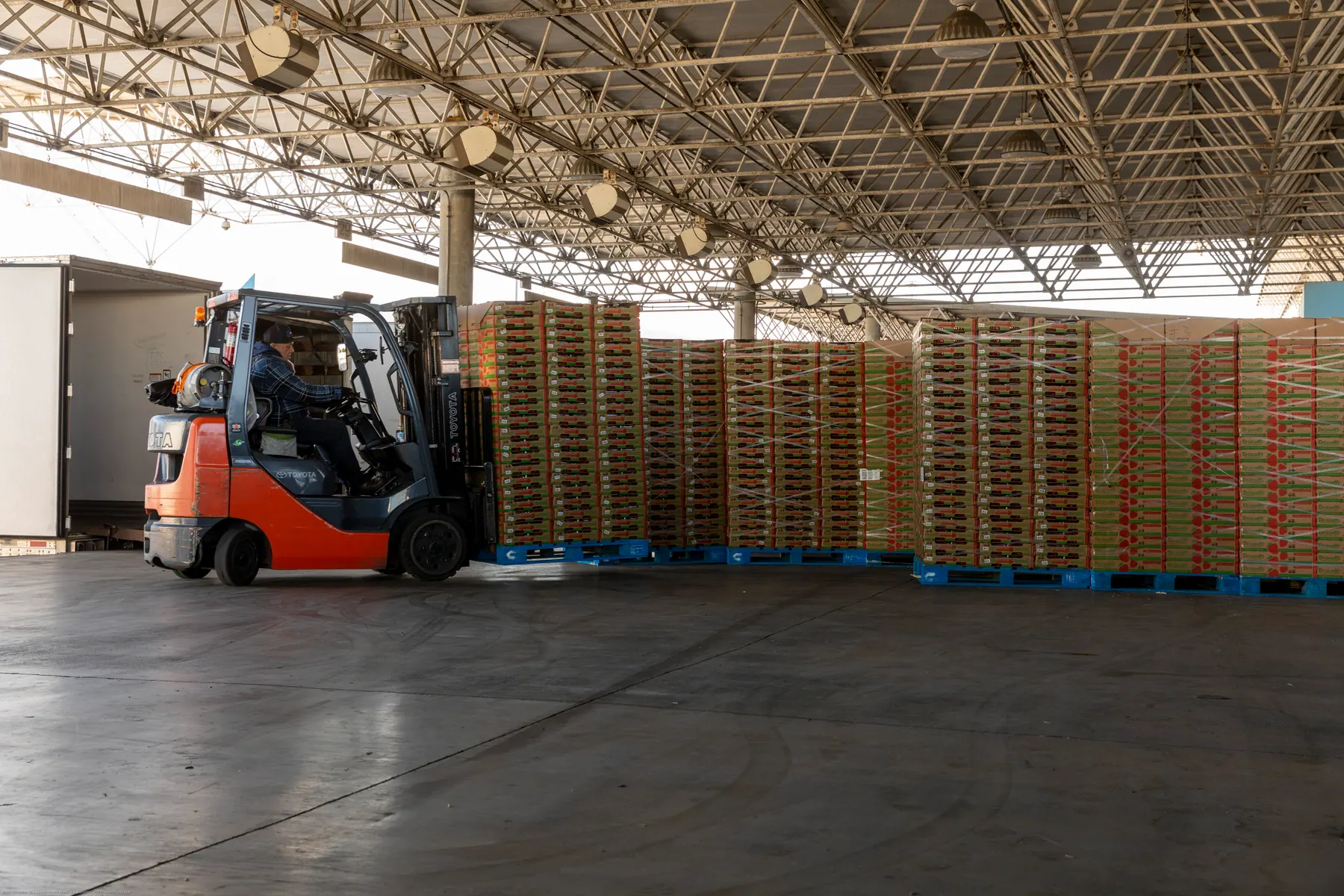 Forklift moving stacked pallets in a distribution warehouse